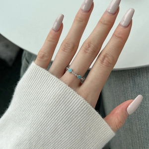 Detail of S925 silver ring featuring blue flower inlay on model's finger in natural light