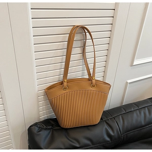 Detail of camel shoulder bag featuring vertical pleated texture and golden metal rings
