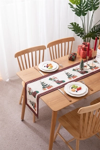 Detailed Christmas table runner with festive tree and stocking motifs on wooden table