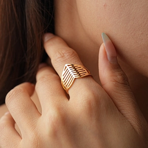 Detail of gold-plated V-shaped hollow geometric ring showing metallic texture on hand
