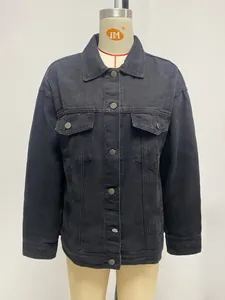 Detail of oversized black washed denim jacket featuring metal buttons and chest pockets