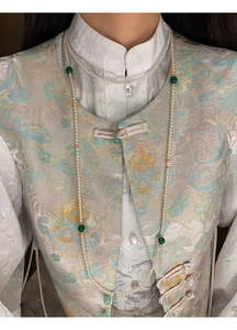 Detail of long pearl necklace with green beads on Chinese style brocade vest