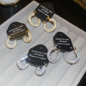 Macro view of gold and silver U-shaped hoop earrings with pave cubic zirconia on grey velvet