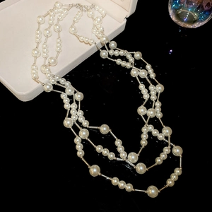 Detailed view of layered pearl necklace with silver metal rods in a jewelry box