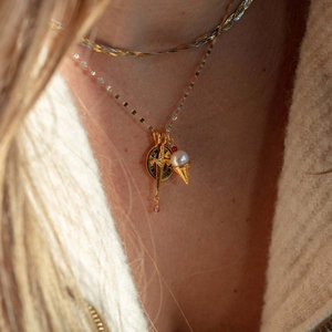 Gold layered necklace featuring sword, round disk, and pearl ice cream cone charms on model