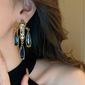 Close-up of vintage drop earrings with blue water-drop crystals and gold alloy detailing