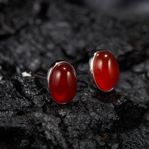 Macro shot of silver studs with oval red gemstones on a textured black surface