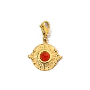 Detailed view of sunburst gold stainless steel pendant with red gemstone and lobster clasp