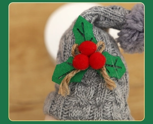 Close-up of grey knitted Christmas gnome hat with red berries and green felt leaf details