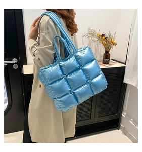 Dettaglio della borsa tote trapuntata blu metallizzato con texture imbottita sulla modella