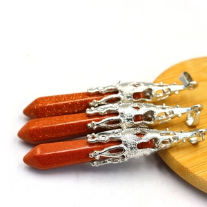 Close-up of gold sandstone hexagonal prism pendants with silver filigree on wood