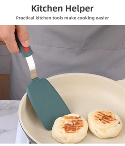 Macro view of dark green heat-resistant silicone spatula head flipping a pancake in a pan
