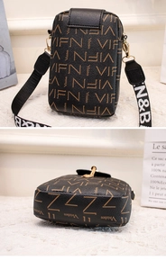 Detail view of black crossbody phone bag with brown letter patterns and wide strap