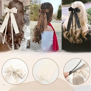 Detail display of long ribbon satin bow hair clips showing metal clip and three colors