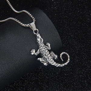 Hip hop style silver crocodile pendant on box chain over a sparkling black background