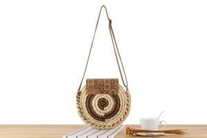 Detail of woven straw circle bag with ethnic print flap on a minimalist wooden surface