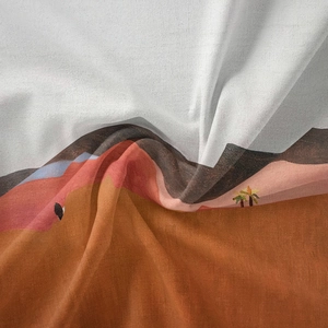 Detailed close-up of bohemian tapestry fabric texture showing sand dunes and palm trees
