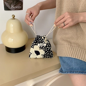 Close-up of floral drawstring storage bag with brand label and portable fabric design