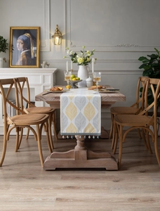 Close-up of jacquard table runner with yellow leaf patterns and decorative tassels