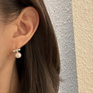 Elegant 925 sterling silver pearl stud earrings shown on model with warm lighting