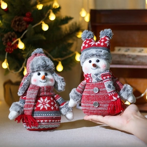 Christmas snowman plush figures with red and grey knitted hats and scarves on festive background