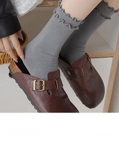 Close-up of grey ruffled knit socks paired with retro brown leather buckle clogs