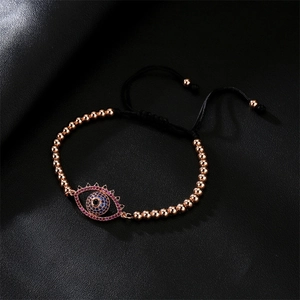 Macro detail of evil eye charm bracelet with blue cubic zirconia on black leather background