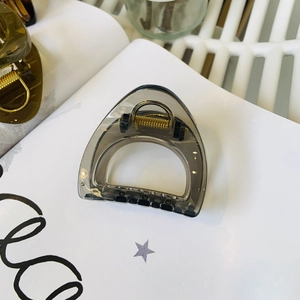 Close-up of translucent dark grey triangle shark hair clip with metal spring detail