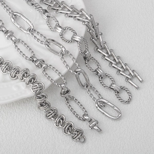 Polished silver stainless steel chains in various designs on a white ceramic plate