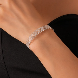 Close-up of hollow geometric floral silver bracelet on wrist with refined metal texture