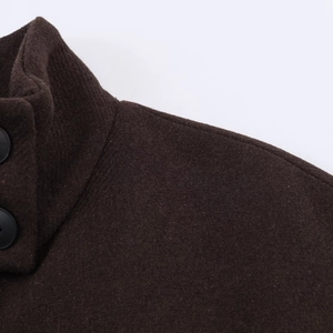Detail of dark brown wool coat featuring a stand collar and matte black round buttons