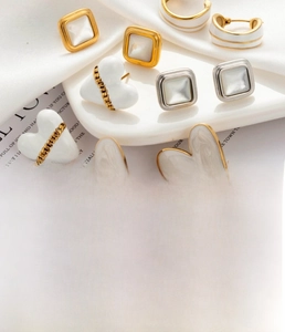 Detailed showcase of titanium steel earrings with cream enamel and gold plated finish
