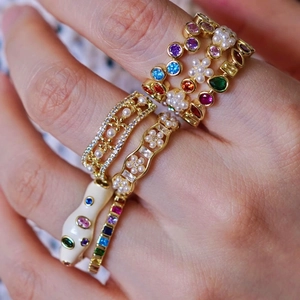Detailed macro view of stacked gold rings featuring pearls and colorful zircons