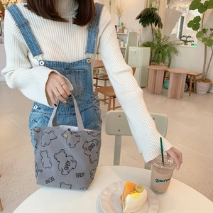 Detail of gray corduroy tote bag featuring cute cartoon bear print and snap button closure