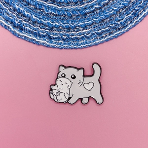 Detail of cute grey cat carrying a white kitten enamel pin with a heart emblem
