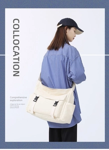Détail du sac bandoulière en toile blanc cassé avec boucles noires et poches latérales