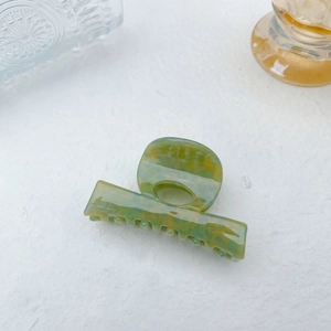 Close-up of green and yellow marble patterned acetate hair claw clip with side engraving