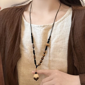 Gros plan d'un pendentif en bois de lotus sculpté sur un collier de perles au style ethnique