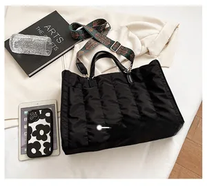 Detailed view of black quilted nylon tote bag with retro patterned wide strap and accessories