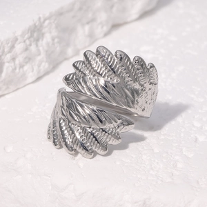 Detail shot of silver wing-shaped open ring featuring intricate feather texture on white stone