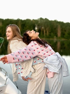 Vue au bord du lac de mannequins portant des pulls en maille rose jacquard et rayés beige