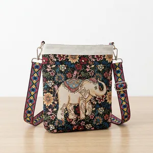 Bohemian canvas crossbody bag with floral elephant embroidery and patterned strap on model