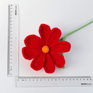 Detail shot of handmade red crochet flower with scale showing 11cm diameter size