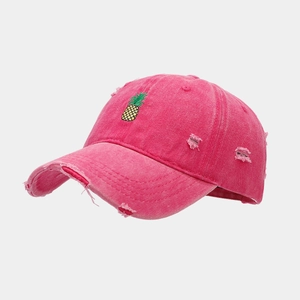 Détail de la casquette rose vieillie avec broderie ananas et bords usés style vintage