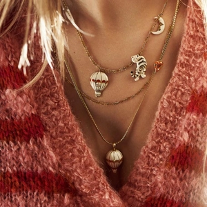Close-up of layered gold necklaces with moon, tiger and heart pendants on a model