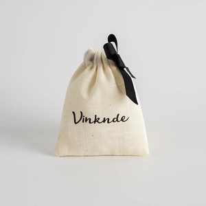 Minimalist off-white cotton drawstring jewelry pouch with a black satin ribbon bow
