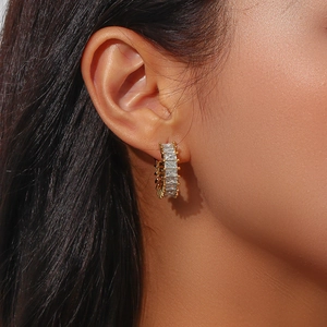 Détail d'une boucle d'oreille en C plaquée or 18K avec zircon rectangulaire sur modèle