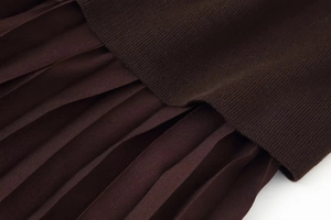 Close-up of knit fabric stitching and pleated material on a coffee brown dress