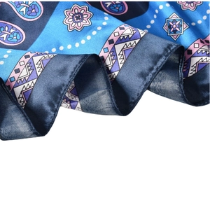 Detailed view of the shiny paisley satin fabric with blue patterns and smooth texture