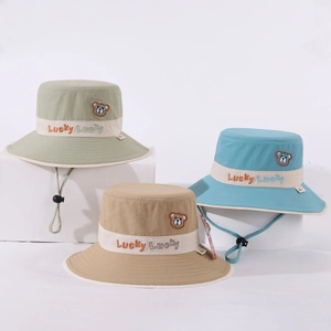 Détail de trois chapeaux bobs pour enfants vert, bleu et kaki avec broderie ours